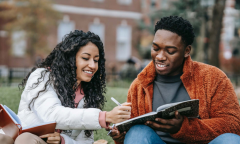 Two students compare notes in university grounds