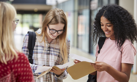 Three pupils get their exam results in a large building